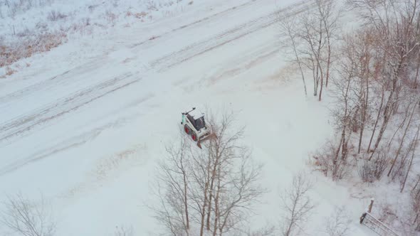 Clearing snow on a rural property with a wheeled bobcat alt