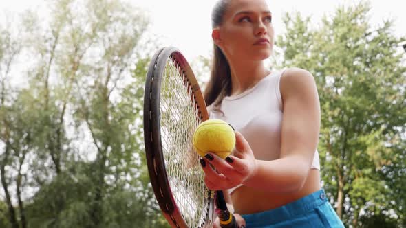 Confident young girl tennis player holding racket and ball ready to serve. Young woman in sportswear alt