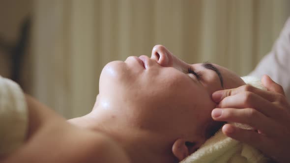 Close Up of Young Woman with a Towel on Head are Receiving a Facial Massage and Spa Treatment for alt