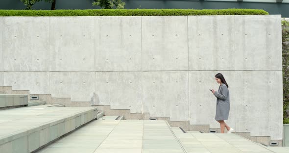 Business woman working on cellphone with walking downstairs at outdoor alt