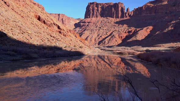 Reflection of red cliffs in Moab Utah as ice floats down the Colorado River alt