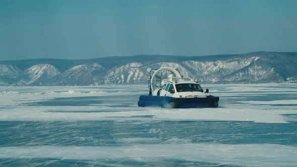 Hovercraft Rides on Frozen Lake Ice Among Snow Capped Mountains