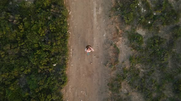 A young girl with a smartphone watching a drone go up alt