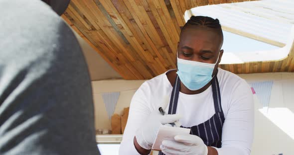 African american man wearing face mask taking order from a man at the food truck alt