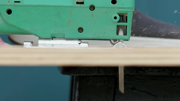 Sawdust Flies Off a Metal Blade As the Jigsaw Cuts Into a Sheet Plywood Workpiece