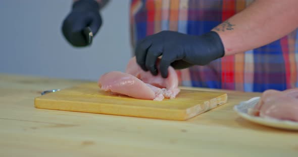 Man Cuts Raw Chicken Meat on a Wooden Board alt
