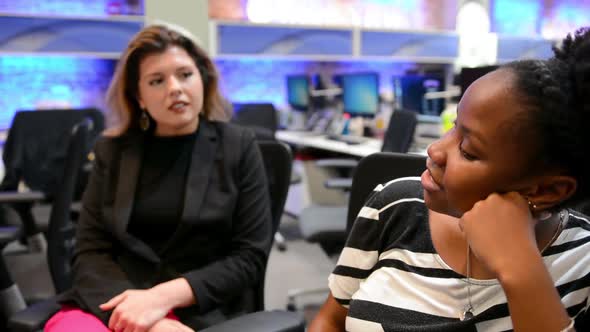 Two young professional women asking and answering questions with each other, biracial alt