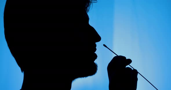 Silhouette of a person doing the covid self test. alt