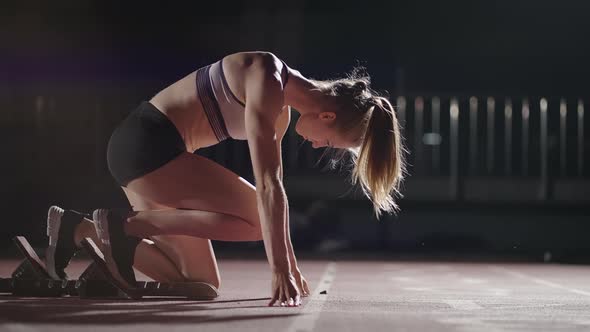 Female Athlete Training at Running Track in the Dark Stadium alt