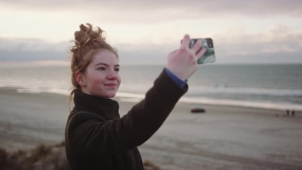 Redheaded Girl Taking Selfie At Beach alt