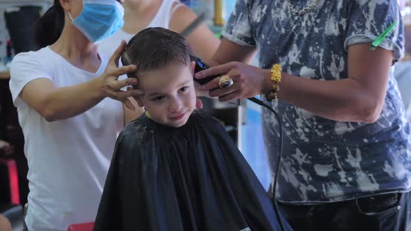 Children's Haircut in the Salon at the Time of the Coronavirus Epidemic. Little Boy Gets a Haircut alt