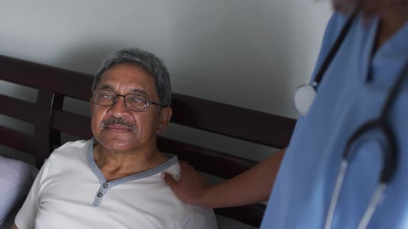 Senior mixed race man with female doctor home visiting and holding hands alt