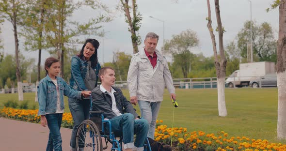Teenager in a Wheelchair Walks with His Family on a Summer Day