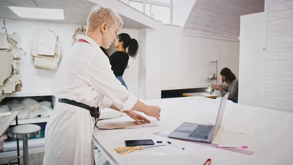 Female Fashion Designer or Tailor of Sewing Workshop is Drawing Pen Around Pattern Which Laying on alt