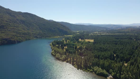 Aerial dolly left of Epuyen lake between mountains covered in pine tree woods, Patagonia Argentina alt