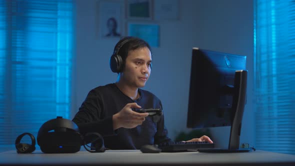 Asian young man playing video game with gaming controller 