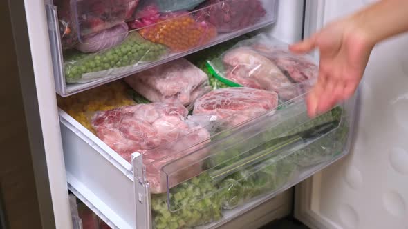 Frozen meat in plastic package in the freezer. Home stock shelf.