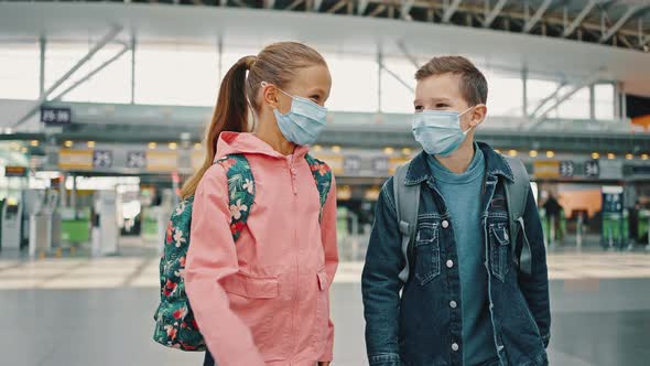 Happy Little Boy and Girl Wearing Protective Medical Masks Walking at Airport Building Talking and alt