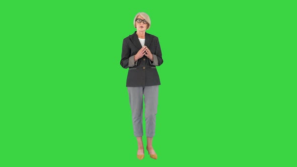 Fashionable Senior Greyhaired Woman in Glasses Talking To Camera on a Green Screen Chroma Key alt