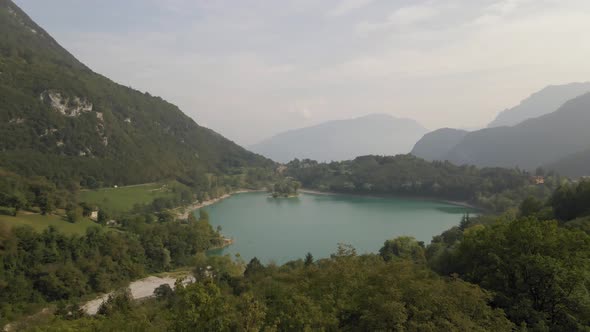 Aerial view: drone shot reveals Tenno lake, Trentino, North Italy. Drone goes up. Green landscape du alt