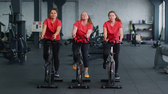 Healthy Caucasian Group of Women Exercising Workout on Stationary Cycling Machine Bike in Gym alt