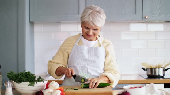 Happy Woman Chopping Cucumber on Kitchen