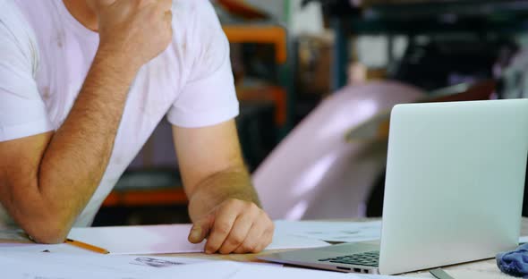 Male mechanic using laptop while sketching car design 4k alt