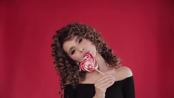 Young Beautiful Girl Holding Tasty Lollipop and Eating It