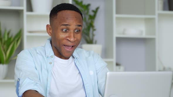 African-American Feels Happy Received Great News By Internet Looks at Pc Screen Raised Hands Scream alt