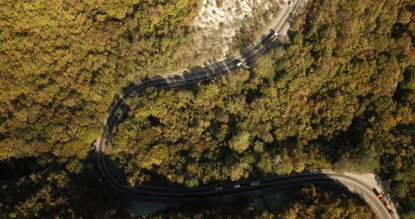 Aerial View of Car Driving Along The Winding Mountain Pass Road Through The Forest Trees. Autumn