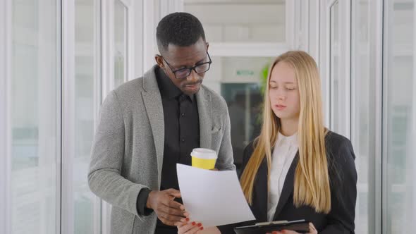 Multinational Business Team of Two People Discuss Annual Report on Project