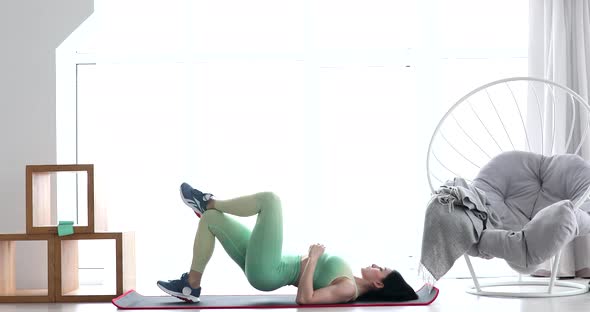 Brunette woman making fitness exercises on mat.