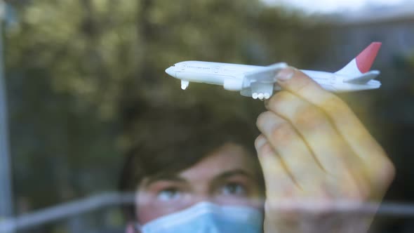 Man Dreams of Flying in Mask Playing Toy Airplane at Home in Quarantine in Self-isolation, Border alt