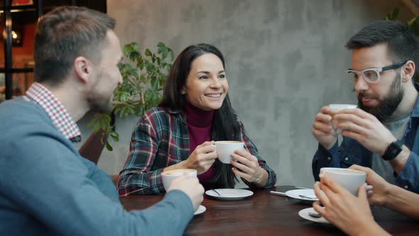 Joyful Friends Male and Female Talking and Drinking Coffee at Table in Cafe alt