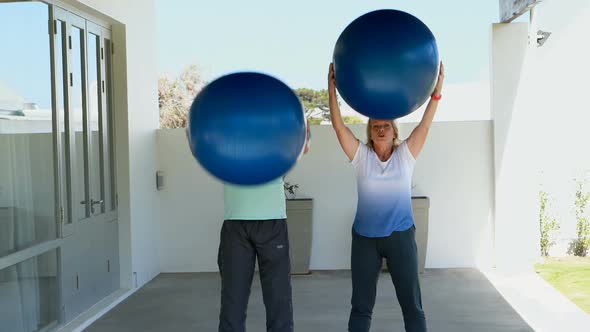 Senior couple exercising with exercise ball alt