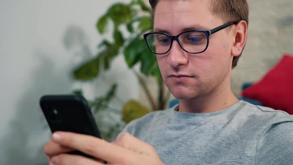 Young Man Surf the Internet Using a Mobile Phone Staying Isolated at Home alt