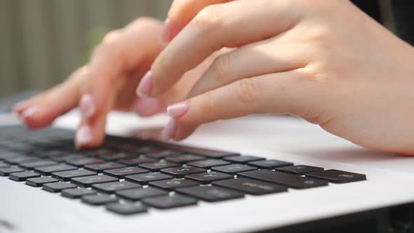 Female Fingers Typing Some Text on Keyboard of Notebook. Unrecognizable Woman Using Laptop Outdoors alt