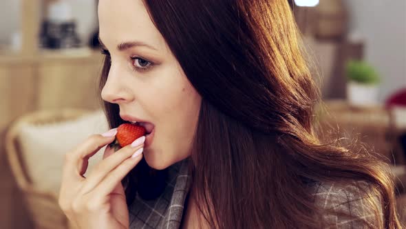 a Woman is Sitting in a Cafe and Eating Strawberries