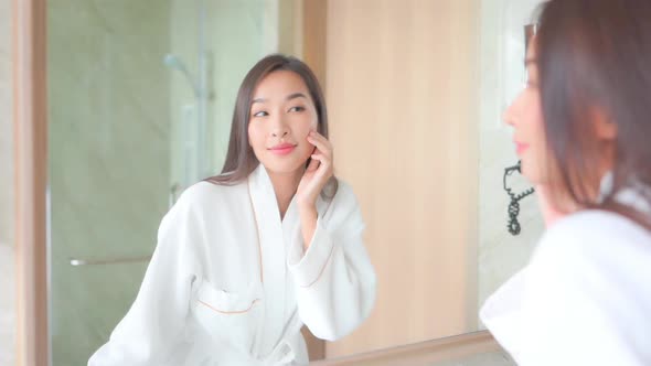Young asian woman check her face on mirror alt