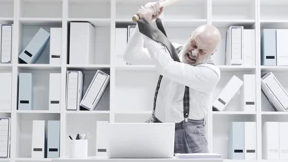 Stressed businessman smashing his laptop with a bat