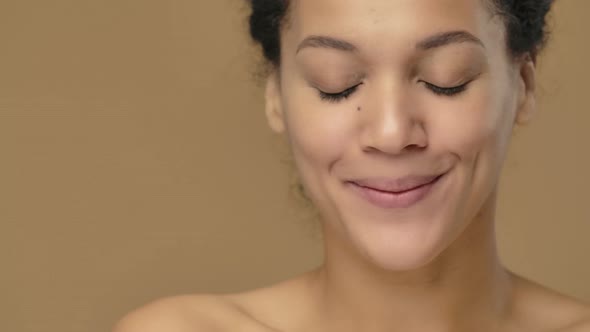 Beauty Portrait of Young African American Woman with Healthy Skin Looking at Camera and Coquettishly alt