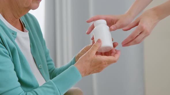 Mature woman patient takes blank white bottle of medicine alt