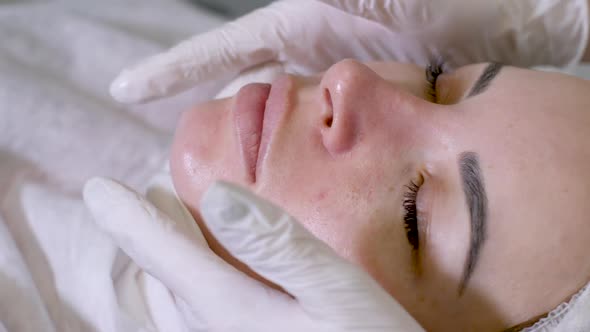 Doctor Beautician in White Rubber Gloves Doing Facial Massage alt