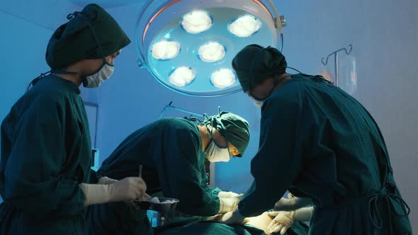 Doctor medical team performing surgical operation surgery in operation room. alt