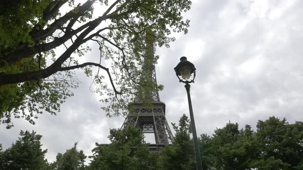 Low angle of Eiffel Tower seen through trees alt