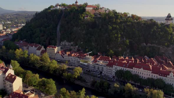 Aerial rising view above Uhrturm clock tower on Graz's Schloßberg dolomite woodland hilltop in Austr alt