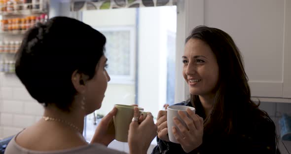 Happy girl friends lesbian couple enjoying a cup of tea or coffee in their ne