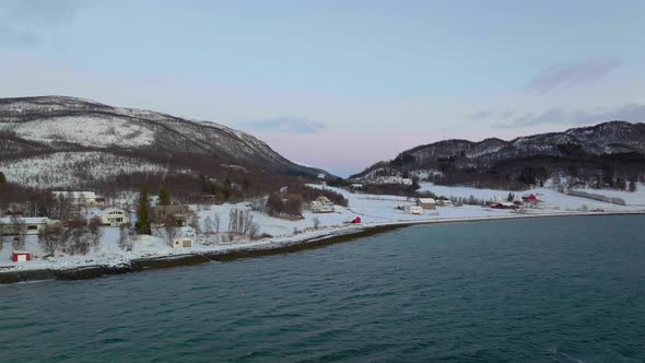 Houses At Arctic Village During Winter Facing The Norwegian Sea At Night. - aerial alt