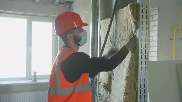 Male Builder in Mask Putting Foam Into Drywall