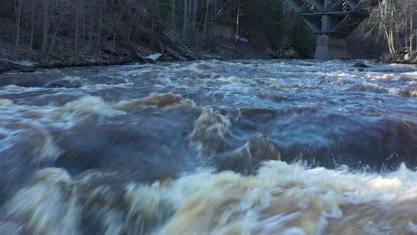 Closeup Drone Shot of a Fast River Surrounded By a Forest on Sunny Day alt